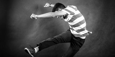 Black and white photo of a man in mid-air performing a dynamic kick.