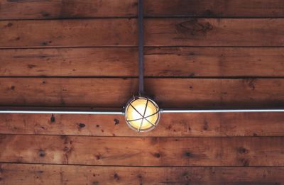 Ceiling light fixture with wooden panels and metal pipes.