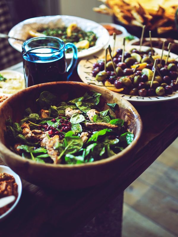 Fresh salad with spinach, chicken, and pomegranate seeds in a wooden bowl.
