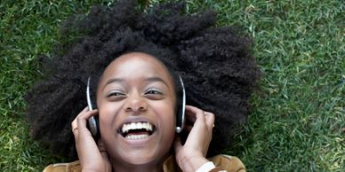 A woman is listening to her favourite podcasts, wearing headphones and is smiling