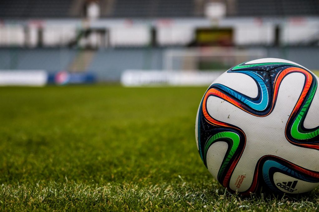 A colorful Adidas soccer ball on a green grass field.