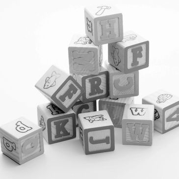 Wooden alphabet blocks stacked randomly on a white surface.