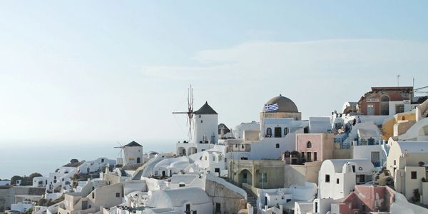 Gennady Podolsky - Bright blue skies and a city view of Greece, white buildings.