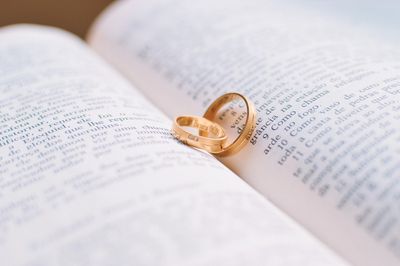 photo of two golden wedding bands resting on an open book, perhaps a Holy Bible