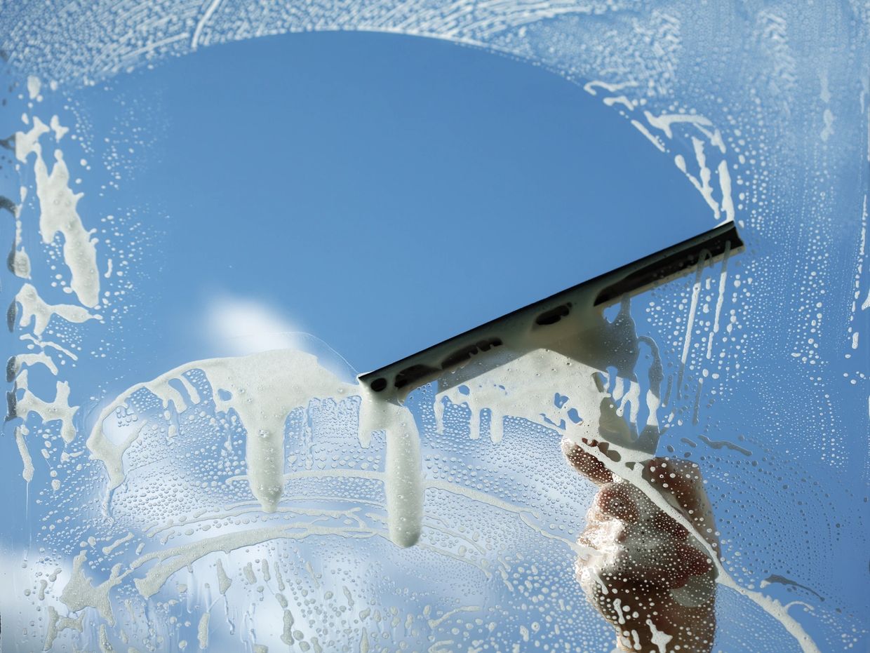 Squeegee cleaning soap bubbles off of window