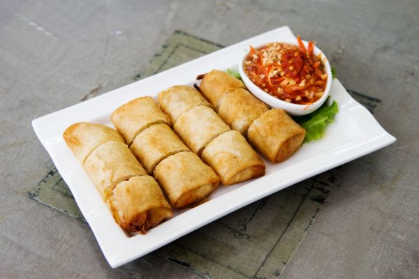 Plate of fried spring rolls with a spicy dipping sauce.