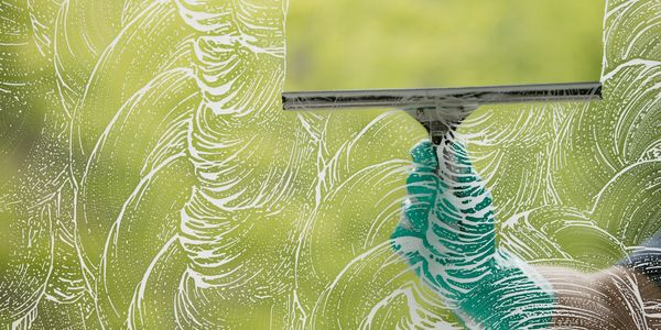 squeegee wiping away soap on a window. 