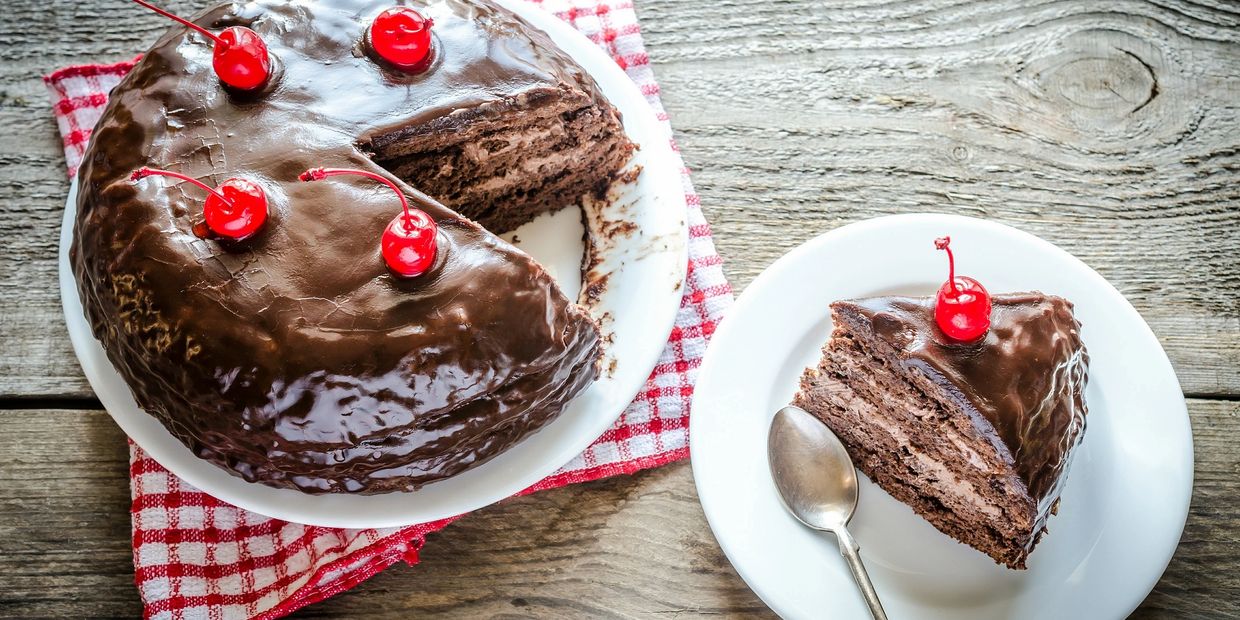 Chocolate cake with cherries on top served on white plates.