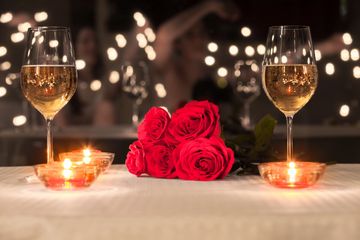 Romantic table setting with red roses and sparkling wine glasses.