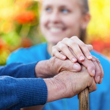 Young female caregiving holding hands with an elderly resident.