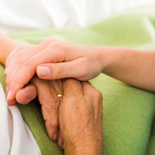 Two hands holding elderly hand.