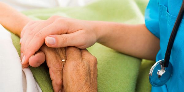 Photo of a nurse holding a senior's hand