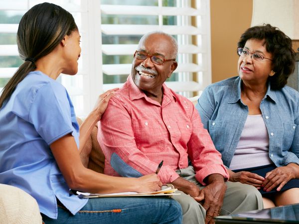 A healthcare professional talks with an elderly couple at home.