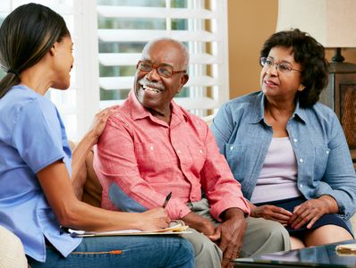 A nurse consulting with an elderly couple in a cozy living room.