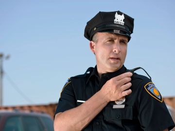 Police officer adjusting his shoulder radio outdoors.