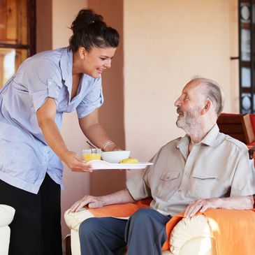 A carer offering a food tray to a patient
