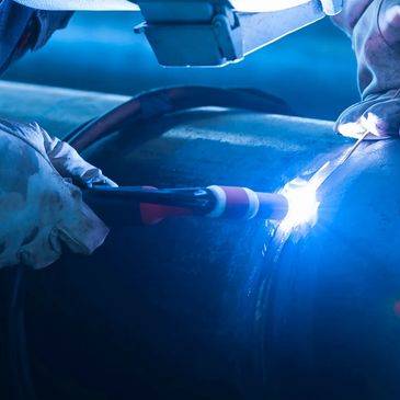 Close-up of a worker welding a metal pipe with bright sparks.