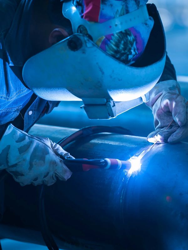 Welding a metal pipe with protective gear.