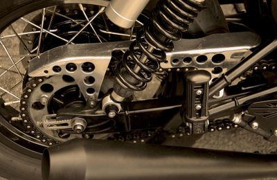 Close-up of a motorcycle's rear suspension and exhaust system.