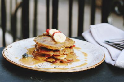 Stack of banana pancakes drizzled with syrup on a plate.