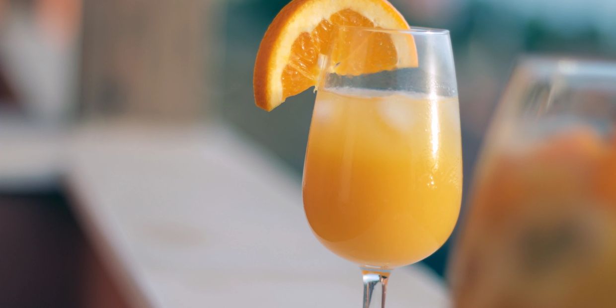 Orange drink with ice and an orange garnish.