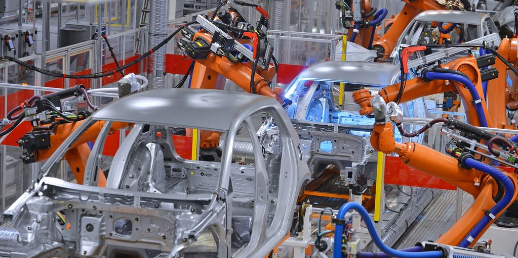 Robotic arms assembling car bodies in factory.
