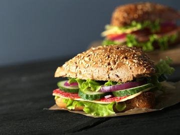 Fresh sandwich with lettuce, cucumber, onion, and meat on seeded bread.