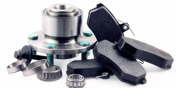Car brake pads, wheel hub, and bearings set on white background.
