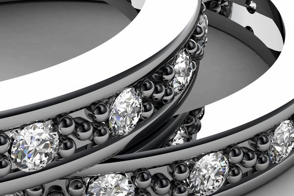 Close-up of silver rings with embedded diamonds and black beads.