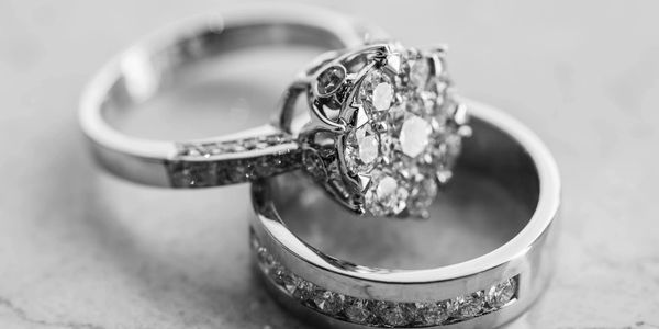 Close-up of two elegant diamond rings on a marble surface.