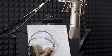 photo of microphone, music stand and sheet music, headphones and acoustic treatment