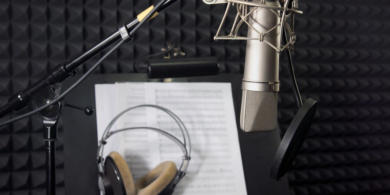 Professional recording setup with microphone, headphones, and music sheets.