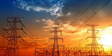 Electric power lines and towers against a vibrant sunset sky.