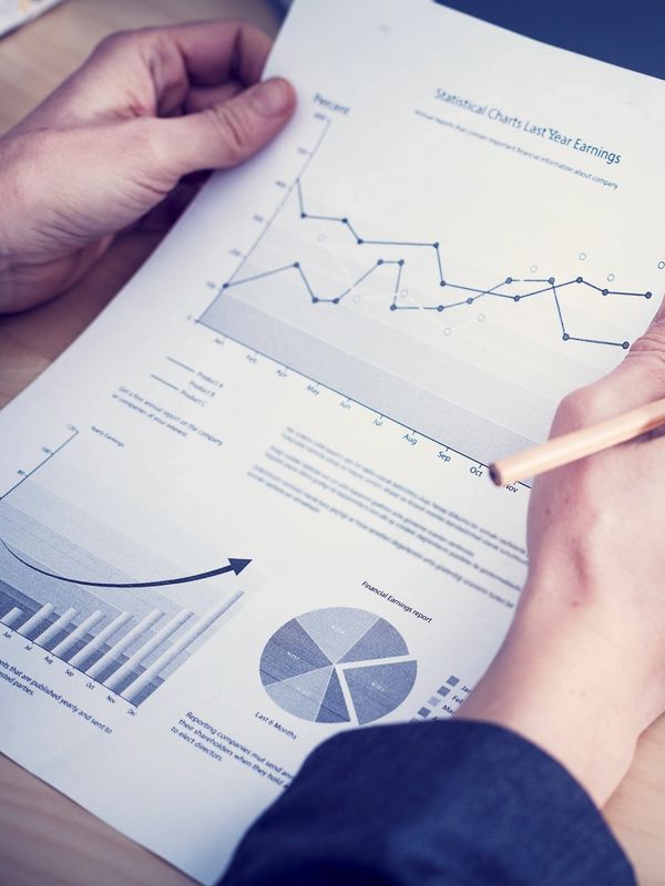 Person reviewing financial charts and reports with a pencil in hand.