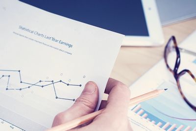 Hand holding a pencil and analyzing a statistical chart on earnings.