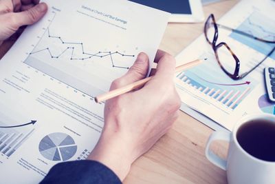 A stock image of someone's hands holding a paper with charts on it. 