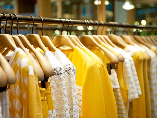Yellow and white clothes hanging on wooden hangers.