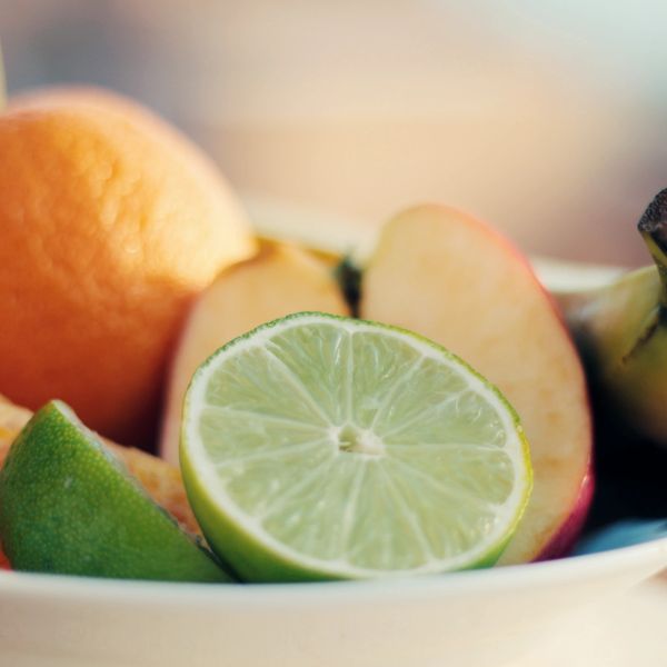 Close-up of mixed fresh fruits including lime, apple, and orange.
