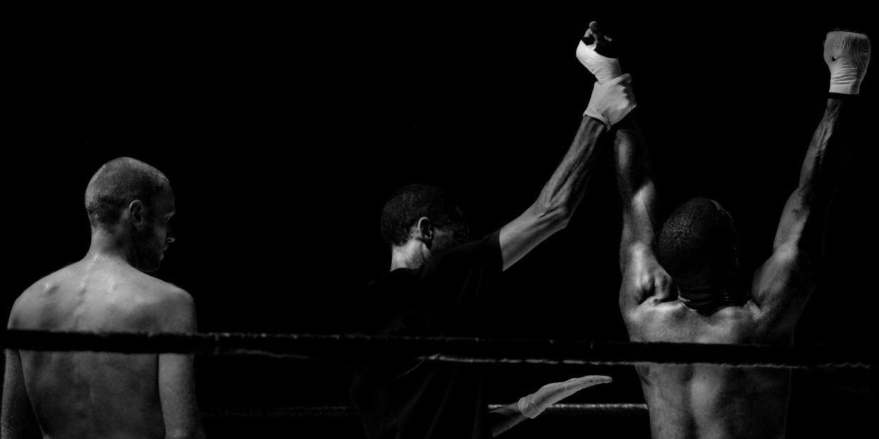 Referee raising the winner's hand in a boxing match.
