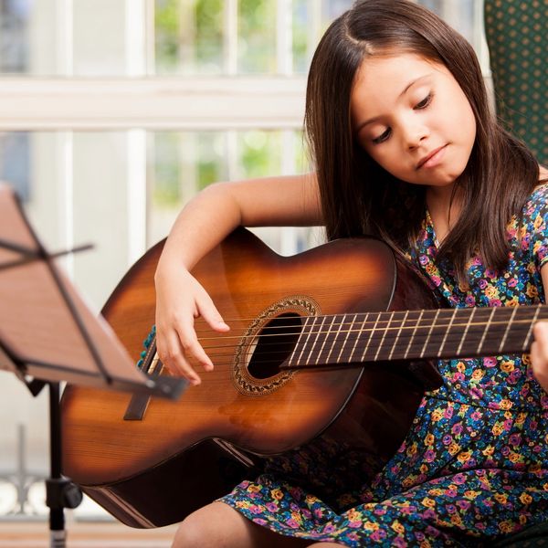A student learning guitar in her music lesson at Mad Music.