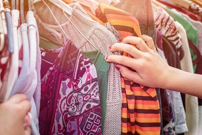 Person sorting through hanging clothing