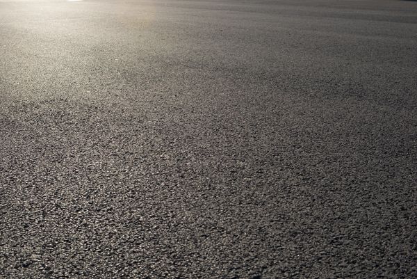 Close-up of a smooth asphalt road surface under sunlight.