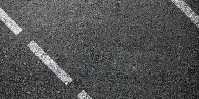 Close-up of asphalt road with white dashed lines.