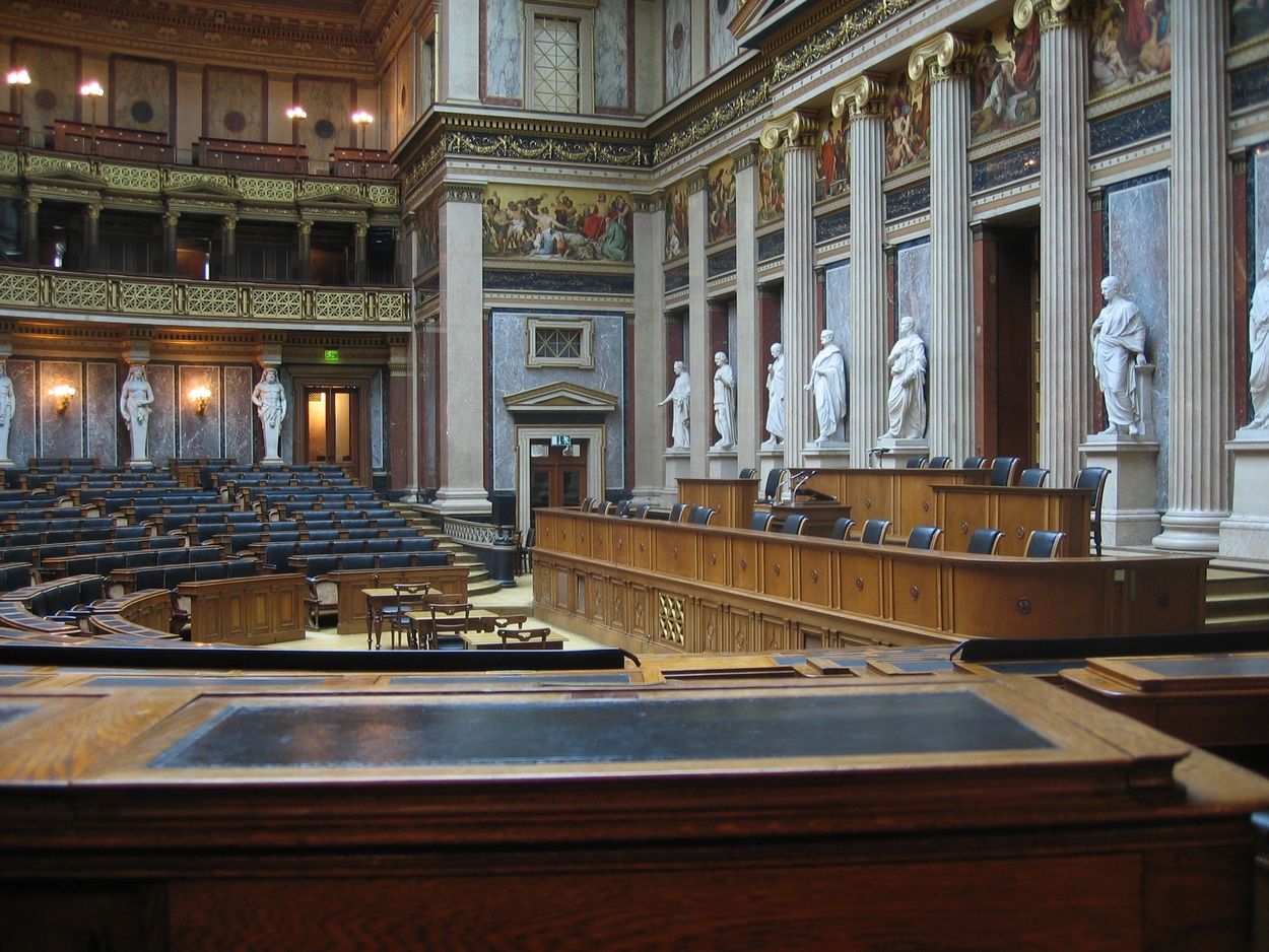 Elegant parliamentary chamber with classical statues and detailed frescoes.