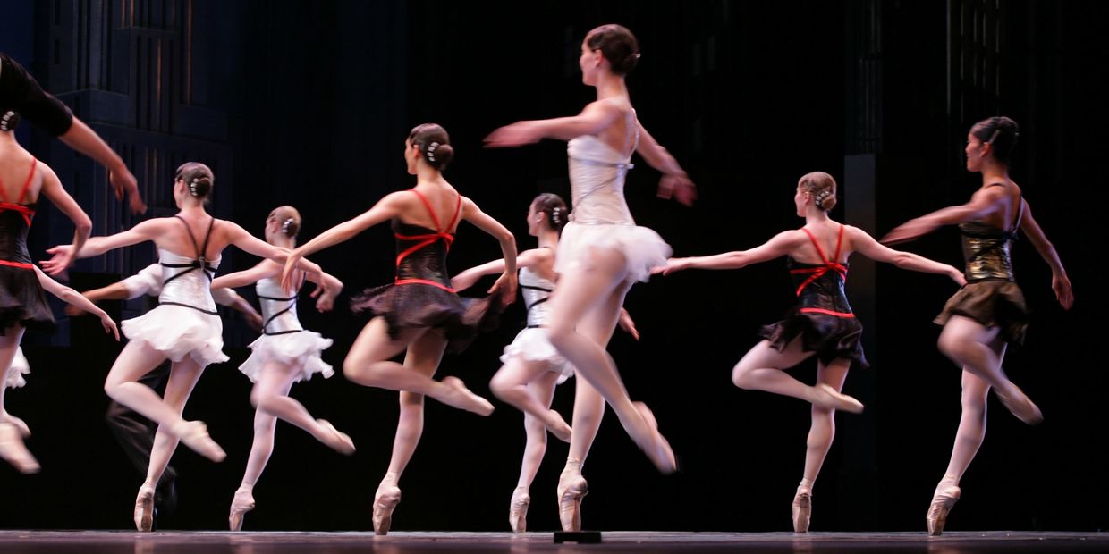 Ballet dancers performing a synchronized routine on stage.