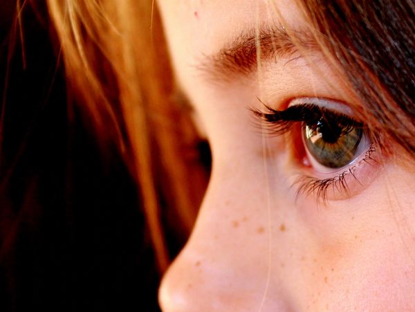 Close-up of a child's green eye with soft lighting and freckles.