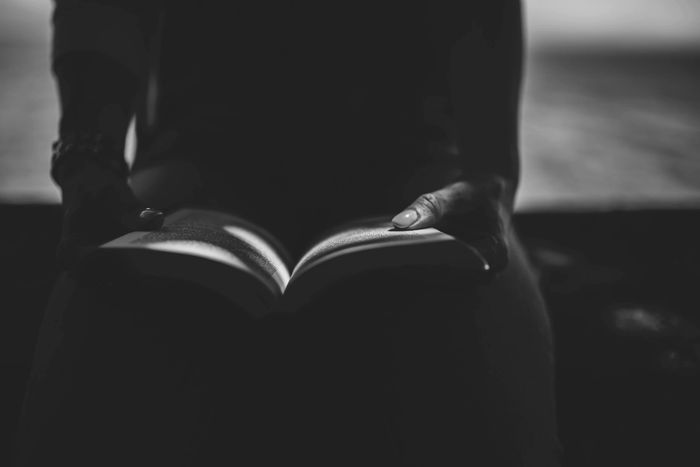 A person seated with a book in his hand reading it.