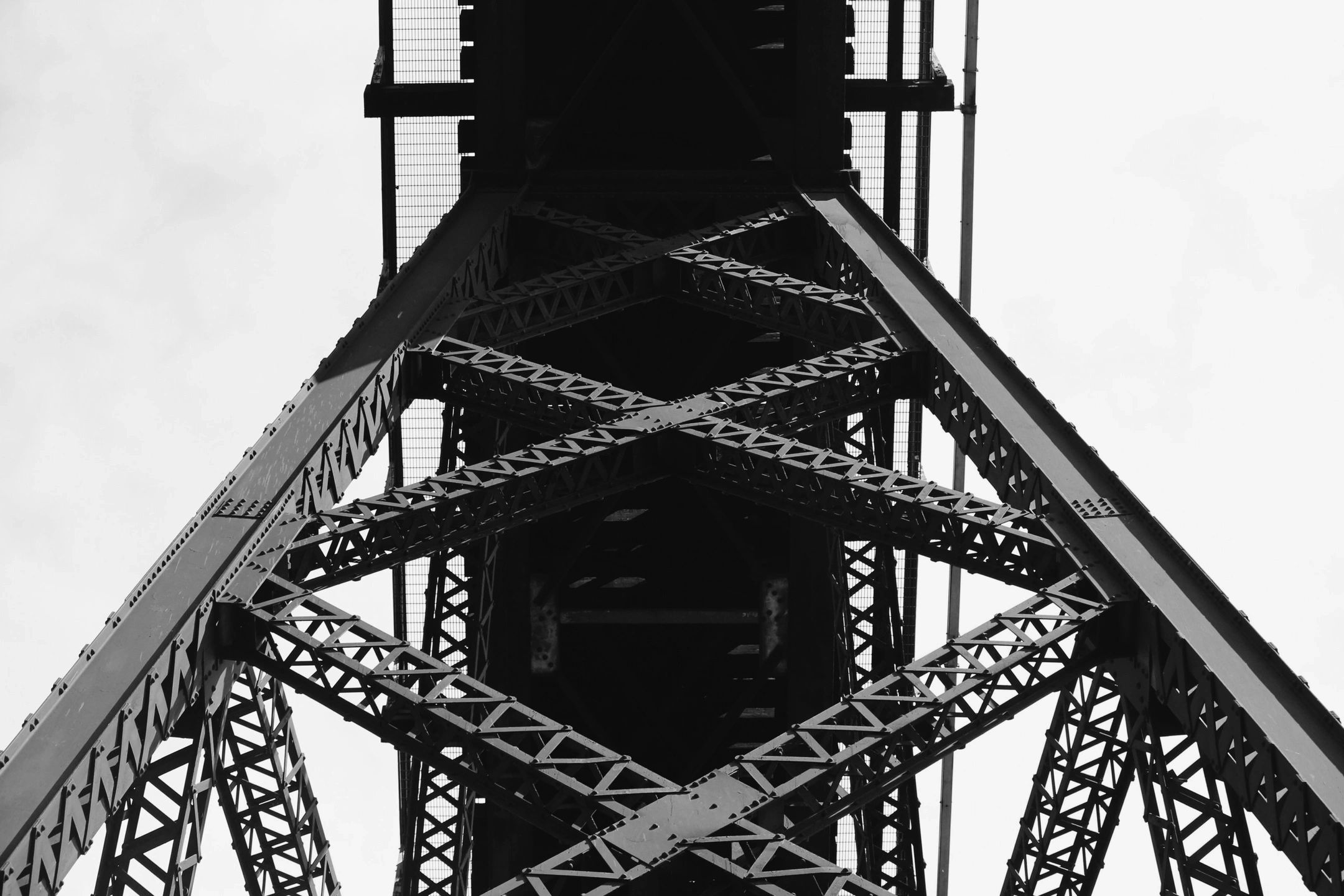 Black and white close-up of a steel bridge's intricate metal framework.