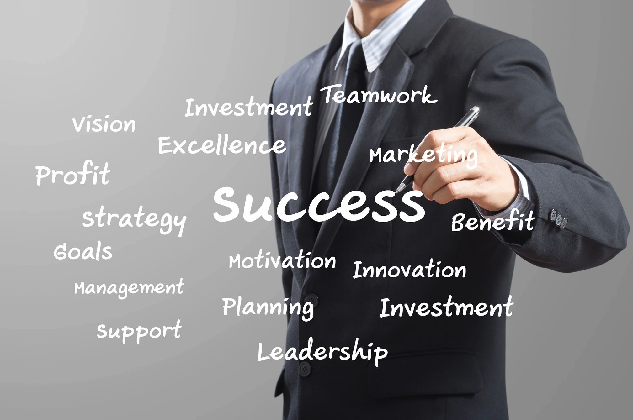 Businessman in suit writing success-related words on transparent screen.