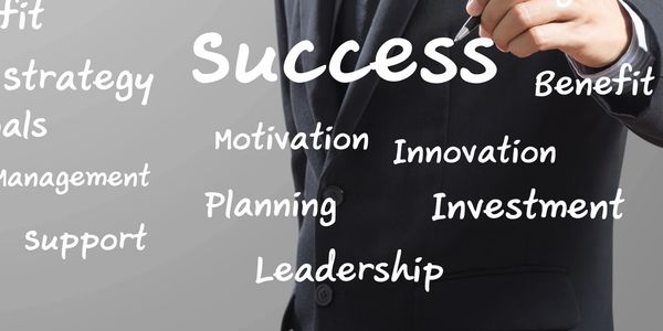 A businessman writing success-related words on a transparent board.